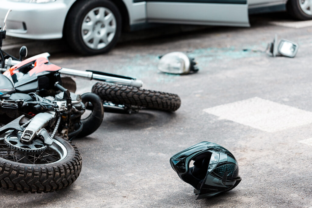 Overturned motorcycle and helmet on the street after collision with a car