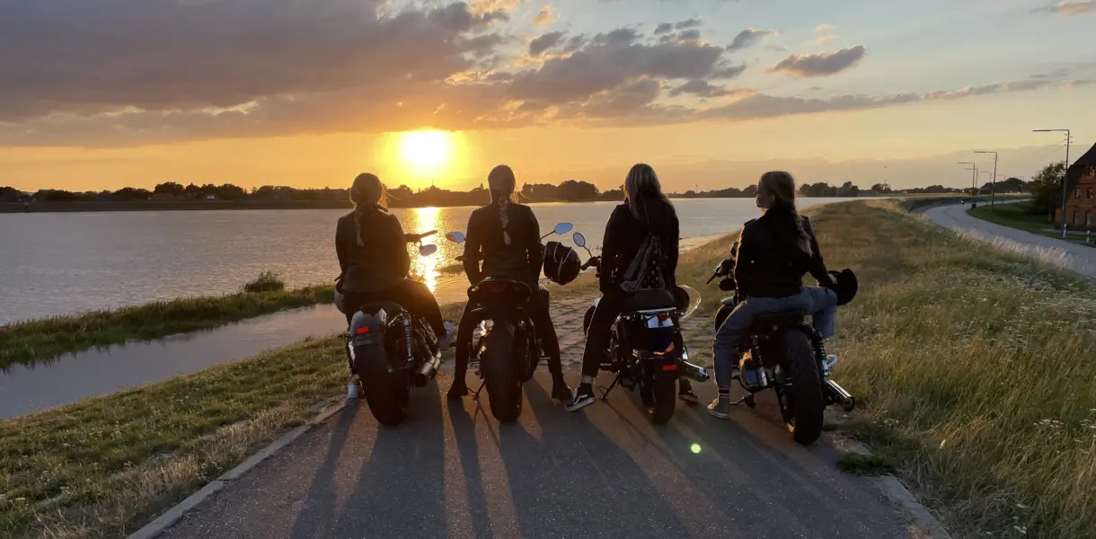 Vier Frauen auf Motorrädern vor einem Sonnenutergang
