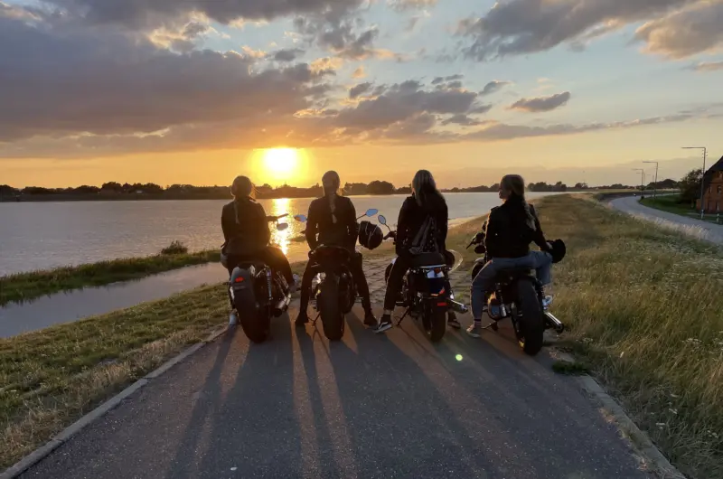Vier Frauen auf Motorrädern vor einem Sonnenutergang
